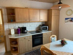 a kitchen with wooden cabinets and a table and a microwave at Ferienwohnungen Rießling in Elend