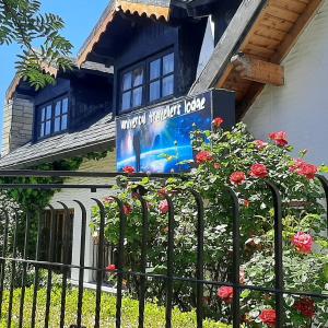 una señal en el lado de una casa con flores en Universal Traveller's Hostel en San Carlos de Bariloche