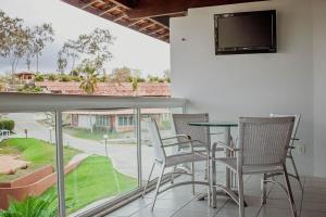 balcón con sillas, mesa y TV en Flat 812 Vila Hípica Gravatá, en Gravatá
