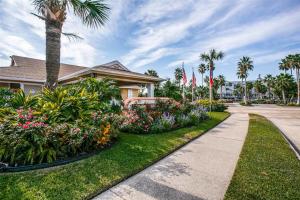 a house with flowering plants and palm trees and a sidewalk at Cove View in Galveston