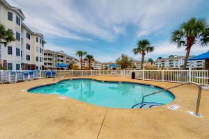 a swimming pool with palm trees and buildings at Palmetto Retreat in Myrtle Beach
