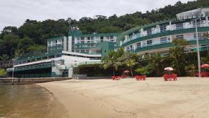 a hotel on the beach with chairs and umbrellas at Angra dos Reis, Angra Inn, Cantinho perfeito in Angra dos Reis