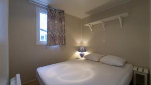 a white bed in a bedroom with a window at Camping Municipal La Prade in Sorgeat