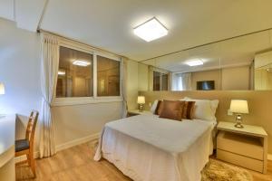 1 dormitorio con cama, escritorio y ventana en Residencial St. Petrus!, en Gramado