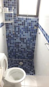 uma casa de banho com WC e uma parede de azulejos azuis em The House Pousada e Hospedagem Enseada- Guarujá no Guarujá