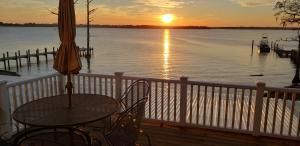a balcony with a table and an umbrella and the sunset at Dances Bay in Elizabeth City