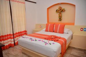 1 dormitorio con 1 cama con una cruz en la pared en Villas Sunrisa, en Zihuatanejo