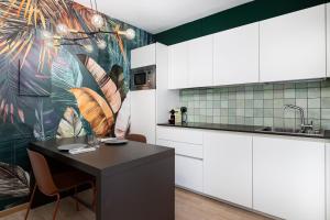 a kitchen with a table and a tropical wallpaper at Stay COOPER l Cà de Bezzi in Bolzano