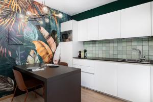 a kitchen with a table and a tropical wallpaper at Stay COOPER l C&agrave; de Bezzi in Bolzano