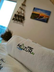 Una toalla en una cama con un cartel. en Relax Houses - Domy Mazur, en Małkinie