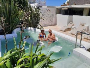 Ein Mann und eine Frau sitzen im Pool in der Unterkunft Misty Waves Boutique Hotel in Hermanus