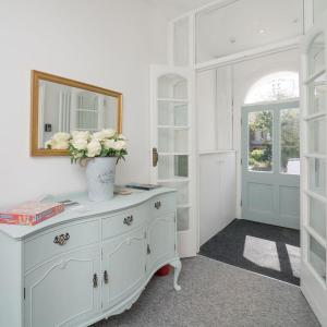 a white room with a vase of flowers on a dresser at Coastal Gem Apartment by Seaside Llandudno in Llandudno
