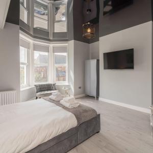 a bedroom with a large bed and a flat screen tv at Coastal Gem Apartment by Seaside Llandudno in Llandudno
