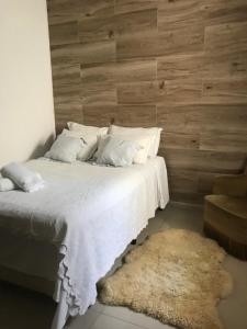 1 dormitorio con cama blanca y pared de madera en Residencial Vila Sassari, en Florianópolis