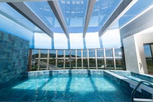 a large swimming pool in a building with a large window at Intercity Portofino Florianópolis in Florianópolis