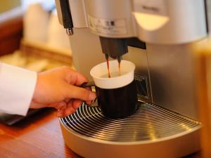 uma pessoa está fazendo uma xícara de café em uma máquina de café expresso em Hotel Route-inn Koriyama Inter em Koriyama