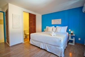 ein blaues Schlafzimmer mit einem weißen Bett mit einem ausgestopften Tier darauf in der Unterkunft Sofia's on the Beach in Búzios