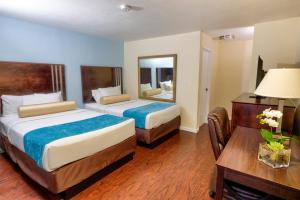 ein Hotelzimmer mit 2 Betten, einem Tisch und einem Spiegel in der Unterkunft Sunrise Inn San Diego in San Diego