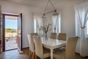 a dining room with a white table and chairs at Stone Villa Kontiani - Red Villa in Dhragoulás