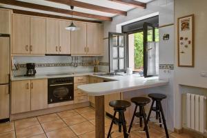 a kitchen with wooden cabinets and a counter with stools at Casas Rurales El Llugarón in Miravalles