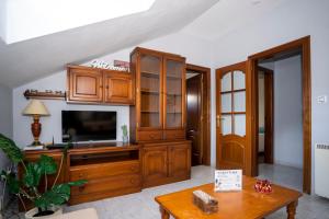 a living room with a tv and wooden cabinets at TuristiQA - Ático Ferrol Centro VUT-CO-02715 in Ferrol