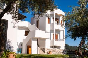 a white building with trees in front of it at Villa Victoria by La Scala Beach in Limenas