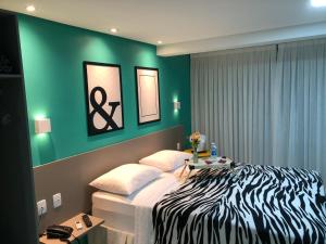 a bedroom with a zebra print bed and a green wall at Magnífico Flat no melhor de Manaíra - Apart Hotel in João Pessoa
