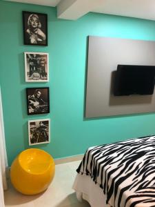 um quarto com uma parede azul com uma cama e um banco amarelo em Magnífico Flat no melhor de Manaíra - Apart Hotel em João Pessoa