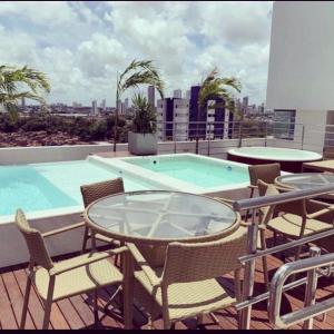 a balcony with a table and chairs and a swimming pool at Magnífico Flat no melhor de Manaíra - Apart Hotel in João Pessoa