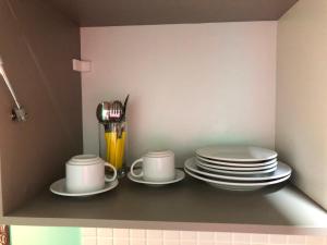 a shelf with plates and cups and saucers at Magnífico Flat no melhor de Manaíra - Apart Hotel in João Pessoa
