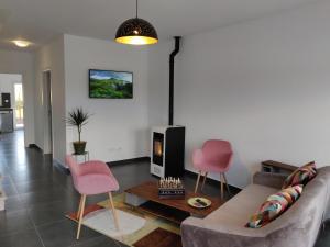 a living room with a couch and two pink chairs at Olive Tree House in Ferrel
