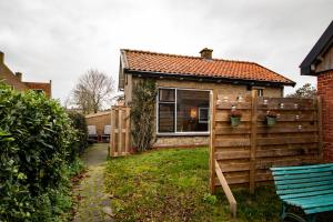 a house with a fence and a blue bench in the yard at De Cel in Nes