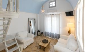 un soggiorno con mobili bianchi e una scala a pioli di Santorini Mesotopos a Firà
