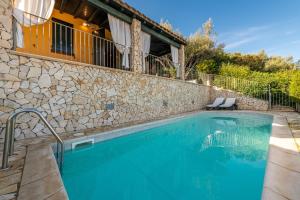 a swimming pool in front of a house with a stone wall at Villa Giglio in Torre delle Stelle
