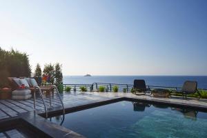 a swimming pool with chairs and a view of the ocean at Root Redrock Yalıkavak in Yalıkavak