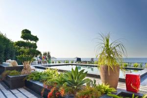 a resort with a pool with plants and the ocean at Root Redrock Yalıkavak in Yalıkavak