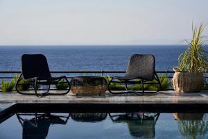 two chairs sitting next to a pool near the ocean at Root Redrock Yalıkavak in Yalıkavak
