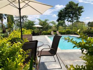 una mesa con sillas y una sombrilla junto a la piscina en Finca Hotel Brasilia, en La Tebaida