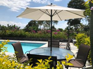 einen Tisch mit einem Sonnenschirm neben einem Pool in der Unterkunft Finca Hotel Brasilia in La Tebaida