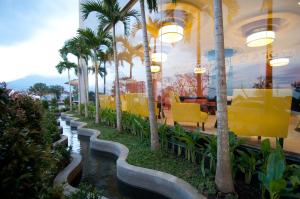 um restaurante com palmeiras e um rio em Aria Gajayana em Malang