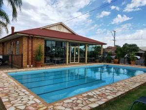 a swimming pool in front of a house at The Oxley Motel Dubbo in Dubbo
