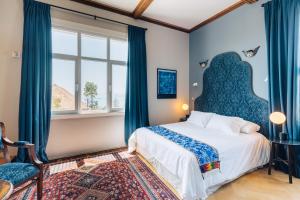 a bedroom with a large bed with blue curtains at Casablu Hotel in Valparaíso