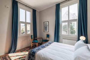 a bedroom with a bed and two chairs and windows at Casablu Hotel in Valparaíso