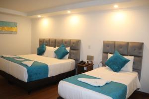 a bedroom with two beds with blue pillows at Hotel Bogota DC in Bogotá