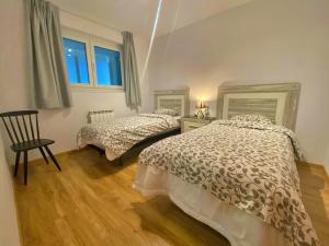 a bedroom with two beds and a chair and a window at Ribasol 422, apartamento hasta 6 personas, Arinsal in Arinsal