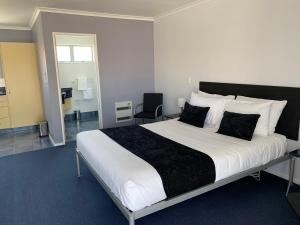  WaipukurauにあるFergussons Motor Lodgeのベッドルーム1室(大型ベッド1台、白黒の枕付)