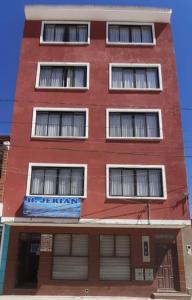 a red building with many windows on the side of it at Hostal Jerian in Uyuni