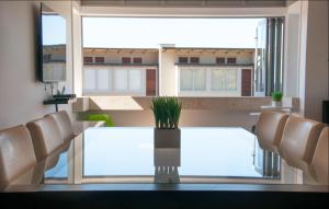 a dining room with a table and chairs and a large window at The Condo On The Beach - Onetangi - Luxury at The Sands by Waiheke Unlimited in Onetangi