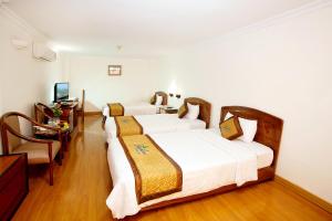 a hotel room with three beds and a desk at Bamboo Green Riverside Hotel in Danang