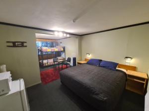 a bedroom with a bed and a desk and a table at Chateau Backpackers & Motels in Franz Josef